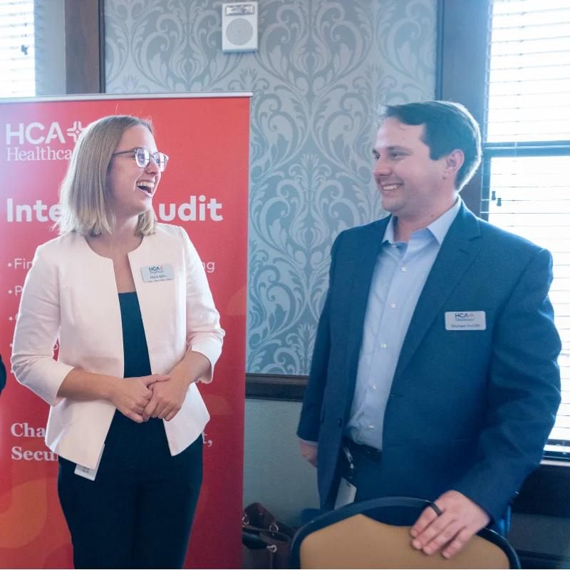 Two HCA Healthcare professionals, a woman and a man, smiling and networking at Belmont's Business & Technology Expo..