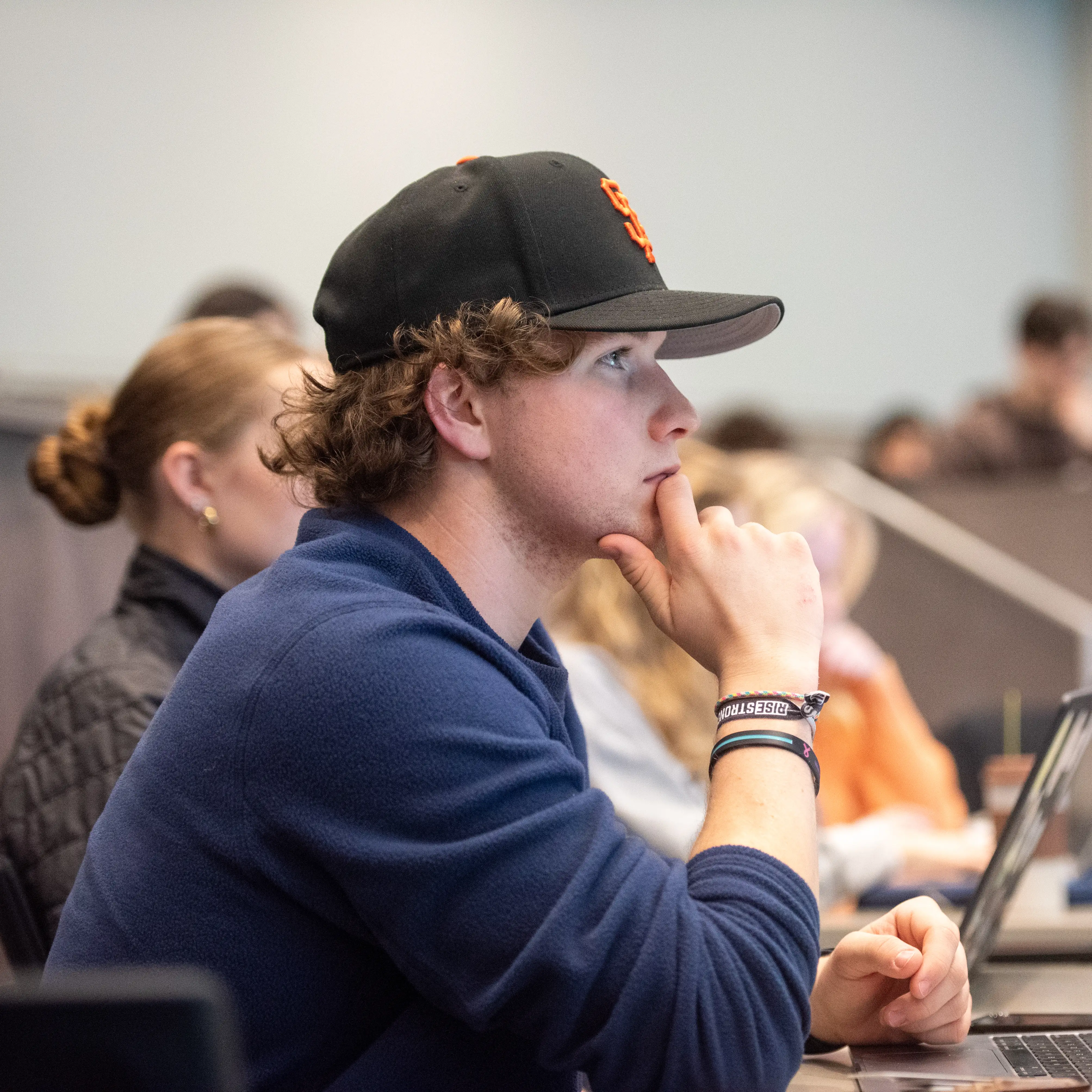 Student listening attentively during a lecture while seated with classmates in a tiered classroom.