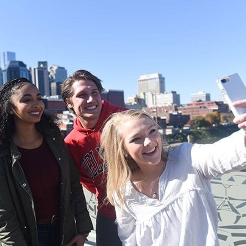 Students taking a selfie on the pedestrian bridge downtown