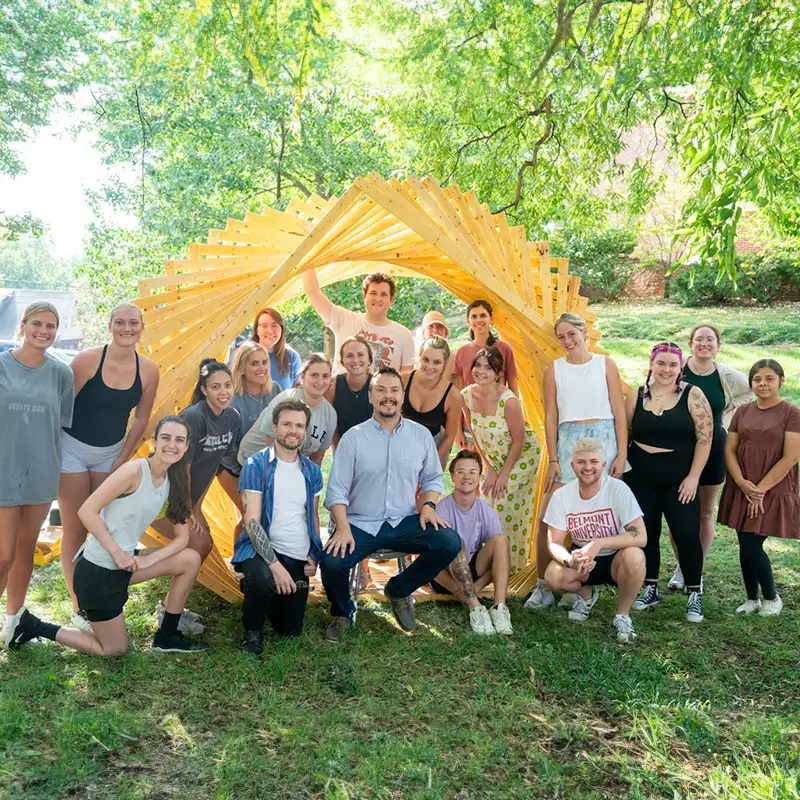 Architecture and Design students stand in fron of the timber twirl that they collaborated on together