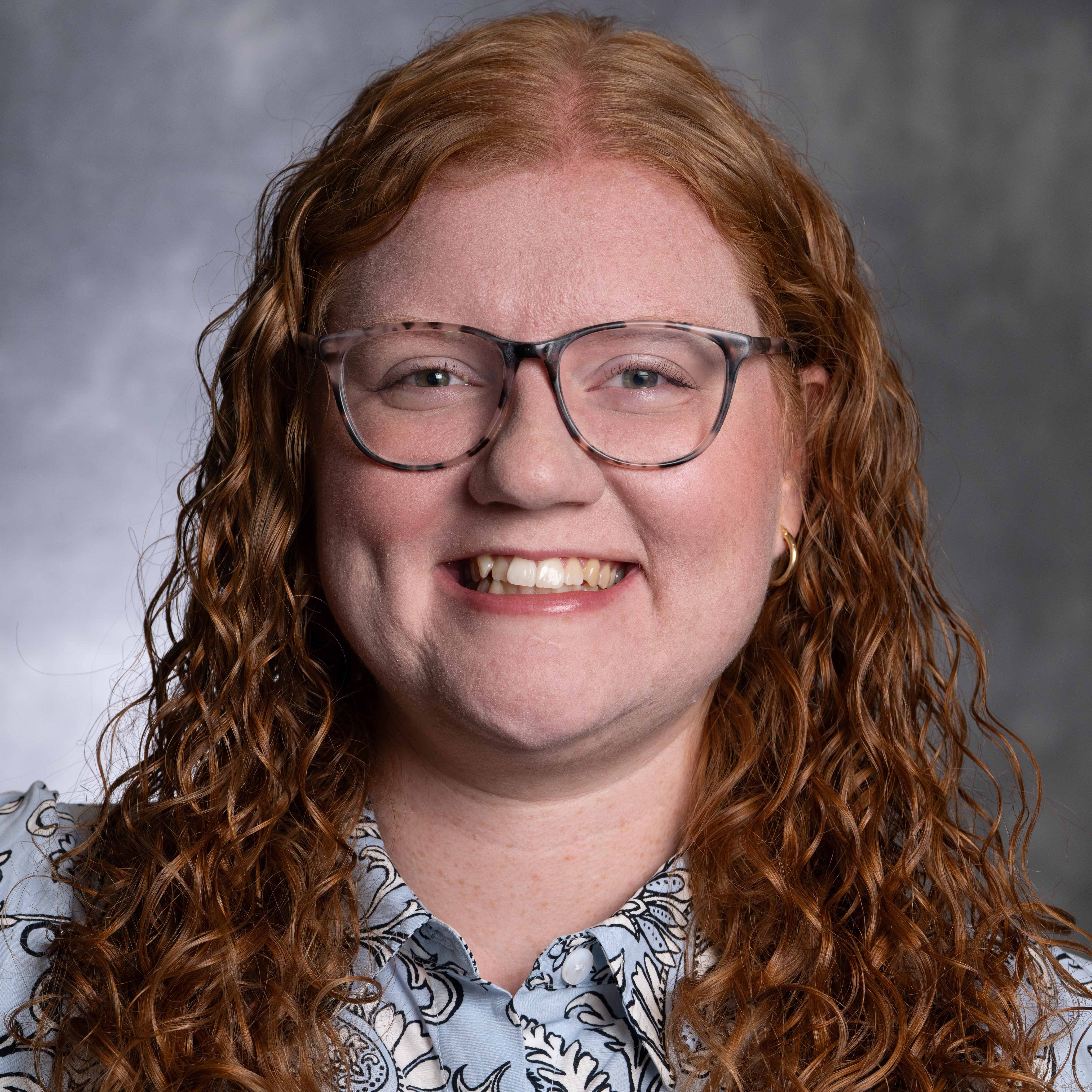 Headshot for Hannah Arning, a woman with curly hair smiling at the camera