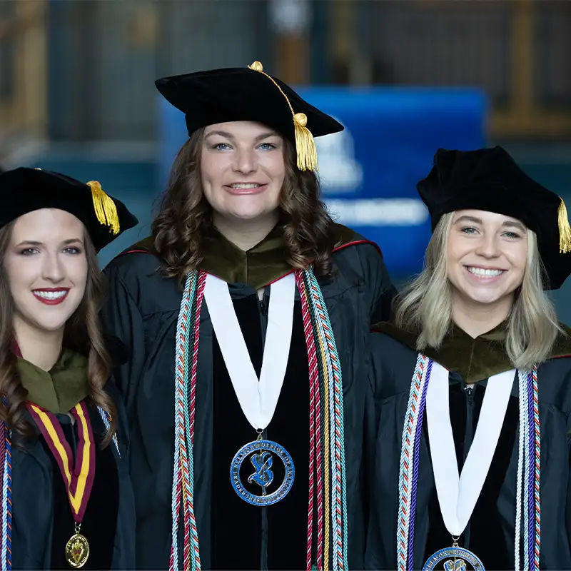 Three female doctoral graduates proudly posing in their academic regalia with honors at Belmont University