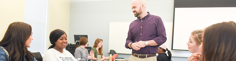 Students leaning in a classroom from their professor