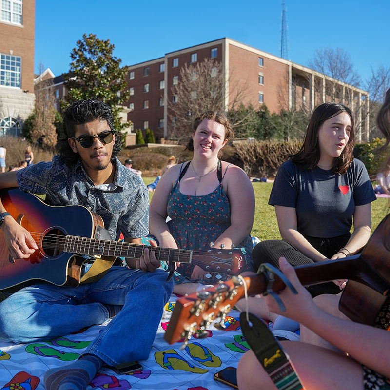 3 students on Belmont's lawn playing music