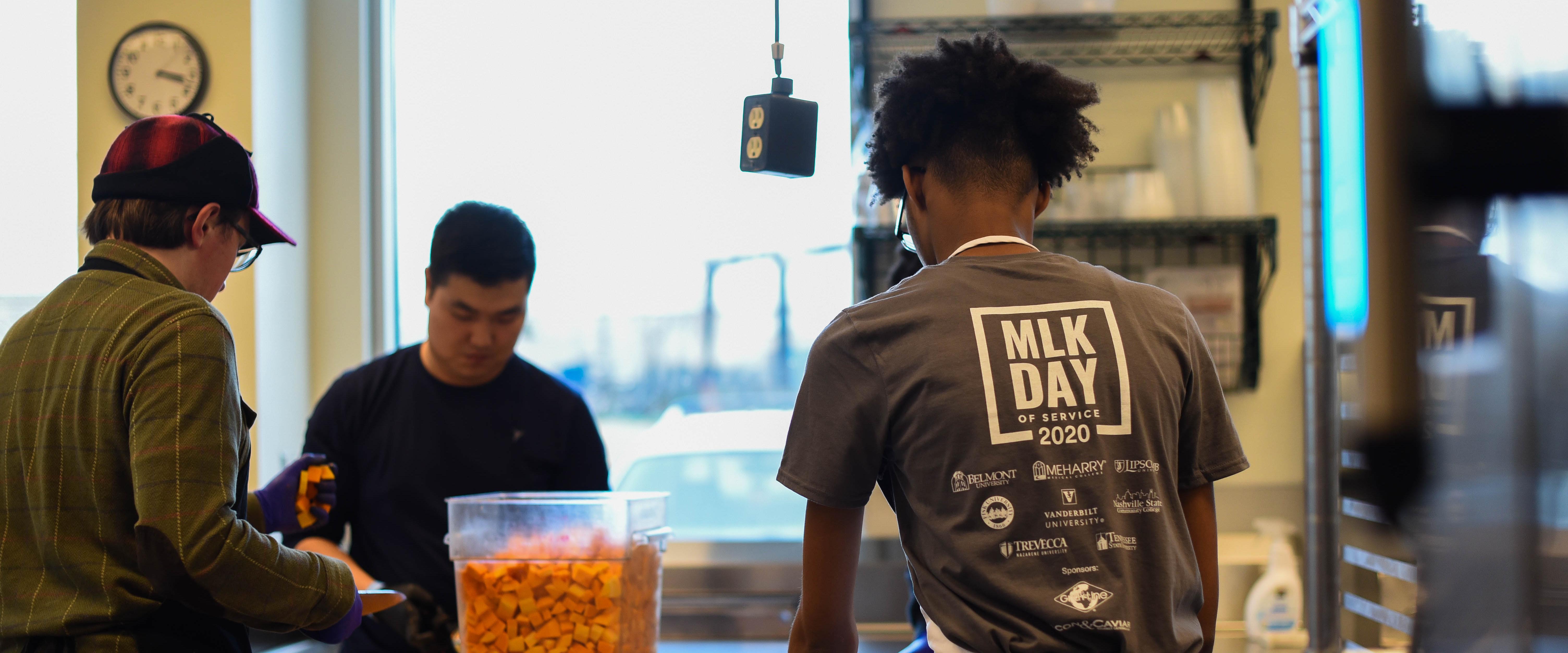 3 student prepping food in a kitchen during MILK day of service