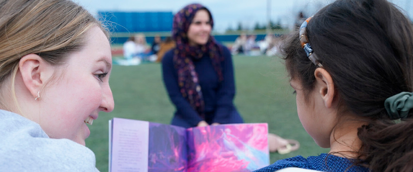 Belmont student smiling while reading to a child at Family Literacy Day