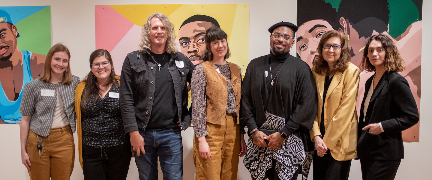 Heriberto Palacio standing in line next to other MFA alumni, in front of his artwork