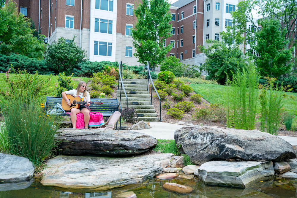 girl playing guitar on campus