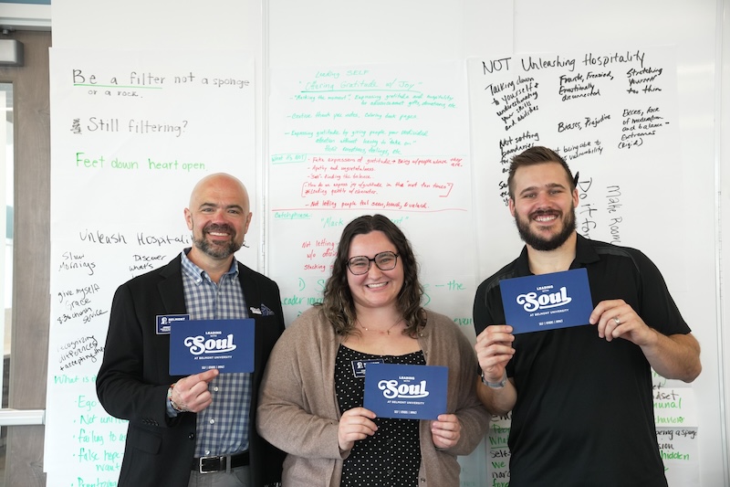 Cora, Jeremy, Joe, smiling in front of group reflection papers