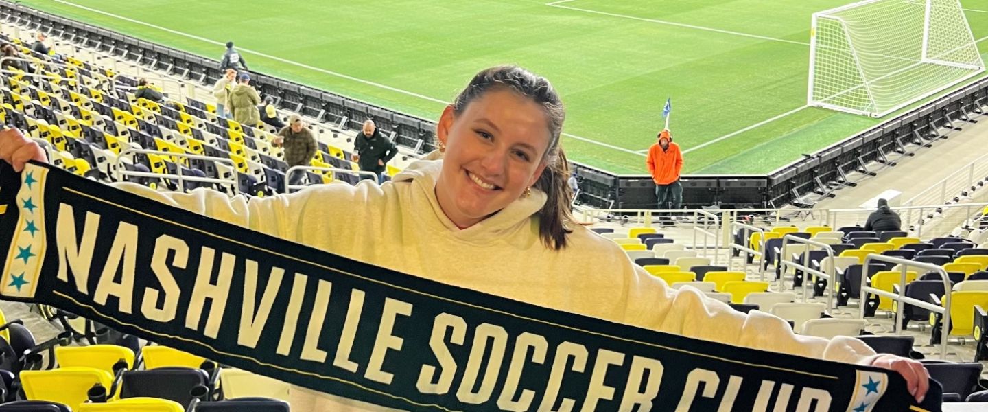 Kathryn Quinn holds up a Nashville SC scarf at Geodis Park