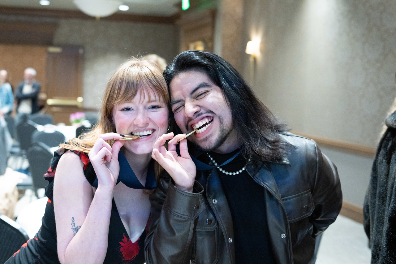 Students playfully bite the gold medallion they receive for graduation from Global Honors