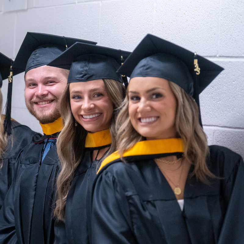 Three student pose before graduation in cap and gown. in 