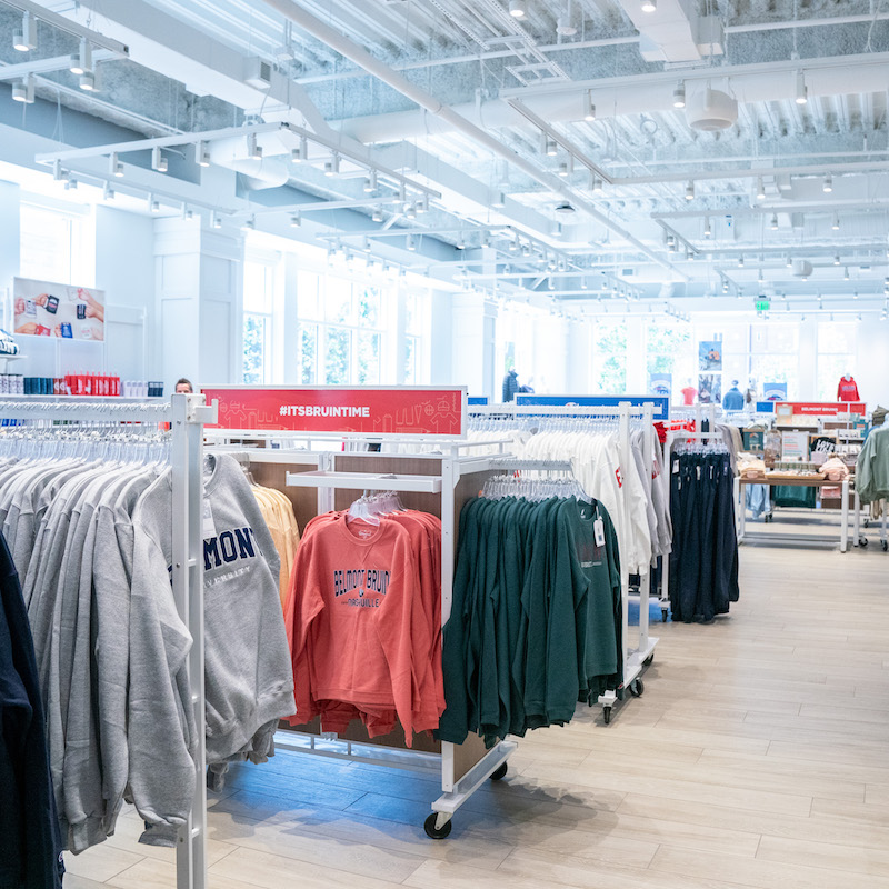 Image of a few racks in The BruinShop, featuring longsleeved and shortsleeved Belmont shirts