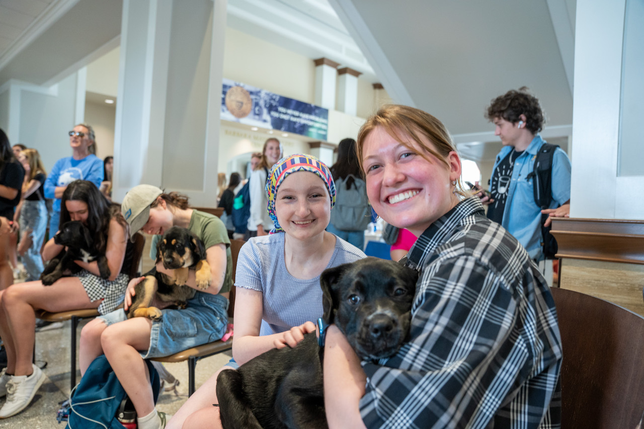 Business students play with puppies at Massey Day celebration. 