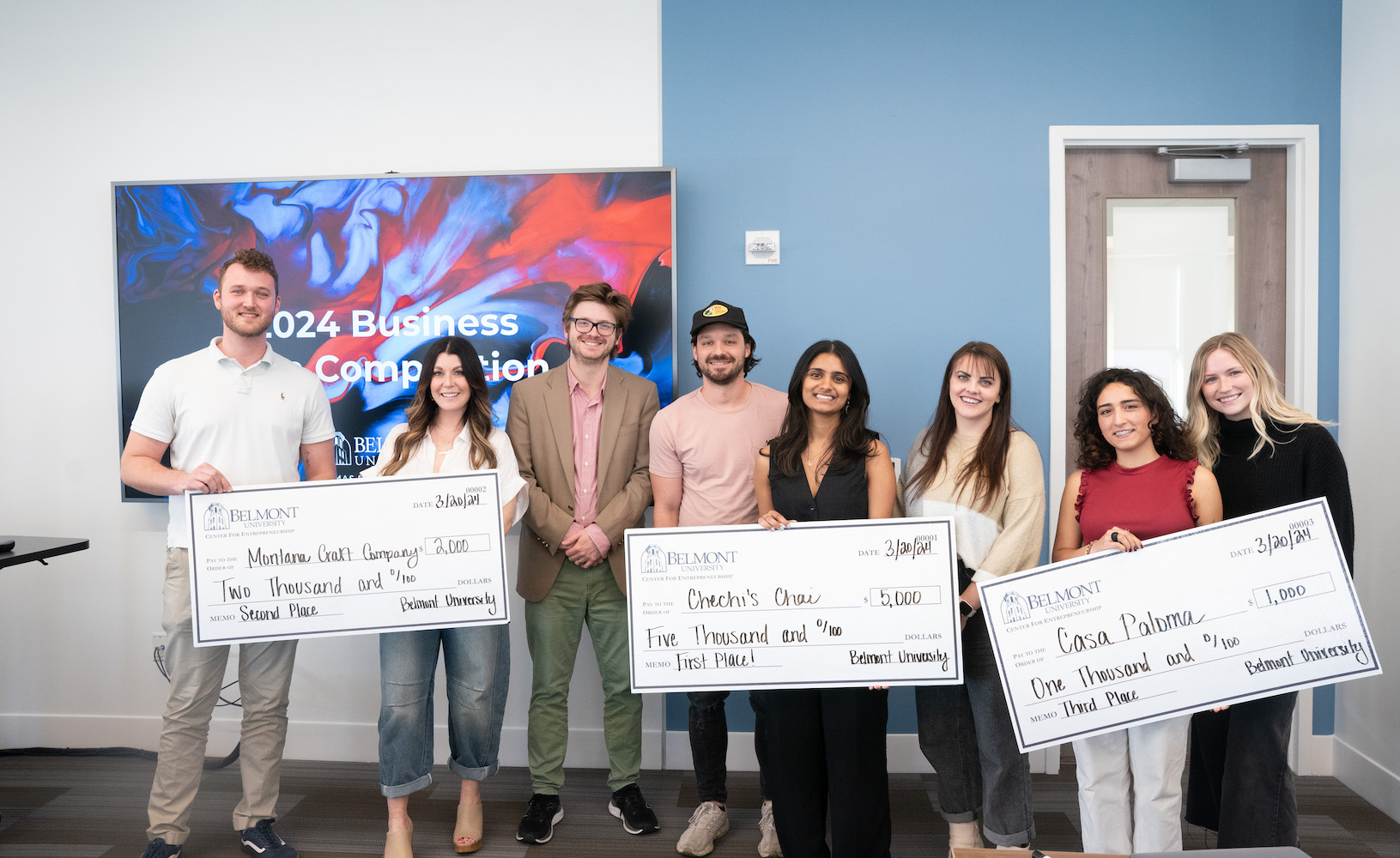 Winners and judges pose with giant checks