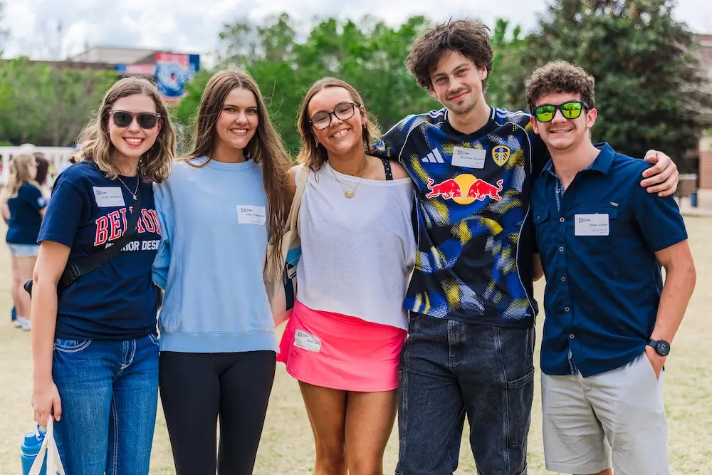 Five students smiling for a group picture on campus