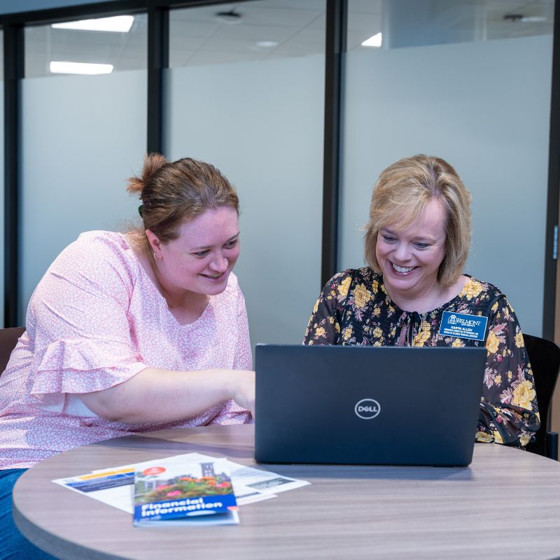 Two people sitting behind a laptop