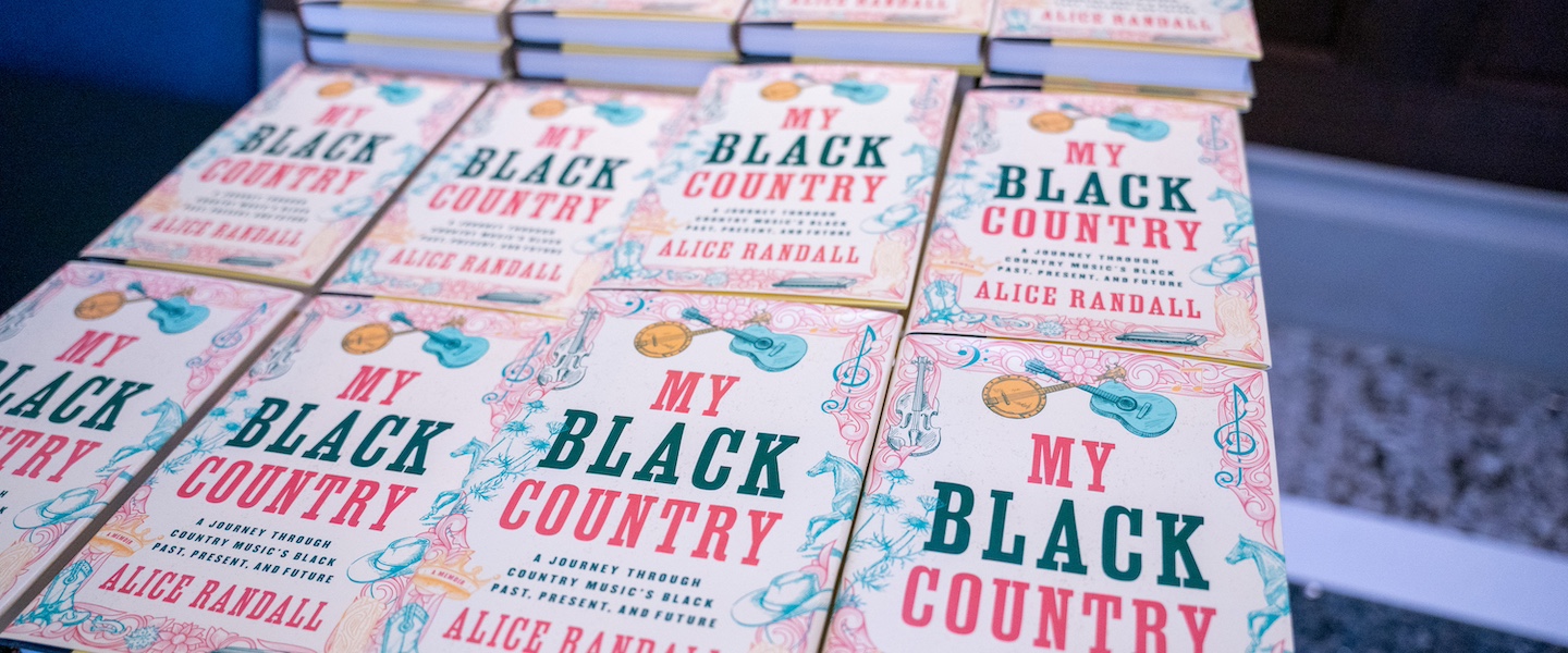 Stacks of books with red and black font and a banjo and guitar with their fretboard overlapping titled "My Black Country"