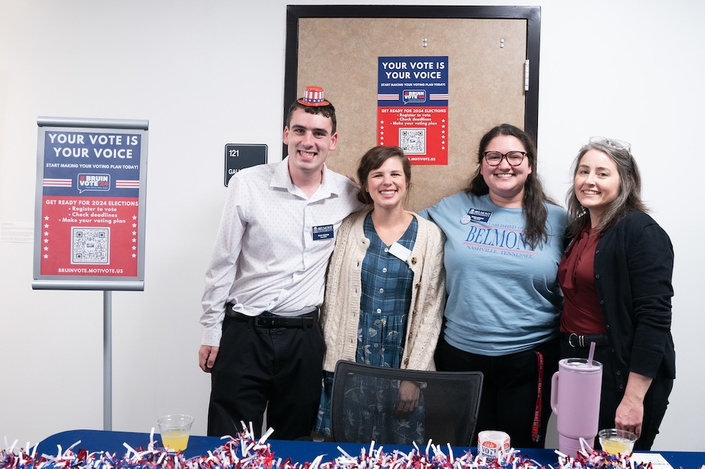 members of the library staff stand at a table to give out voter registration information