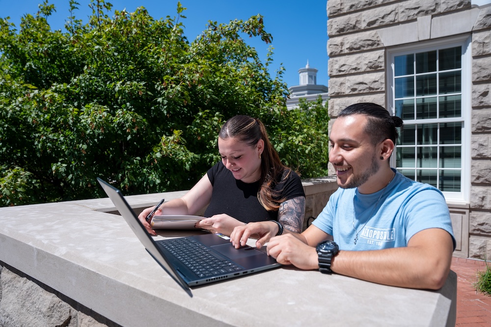 two students working together to study outside on campus