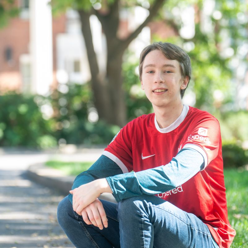 Max Goskie sits on the curb in a Liverpool FC kit