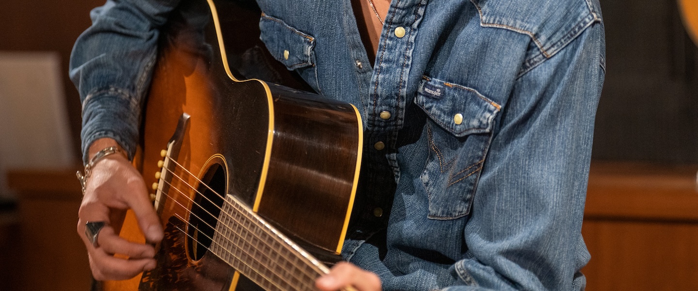 zoomed in photo of a male strumming a guitar