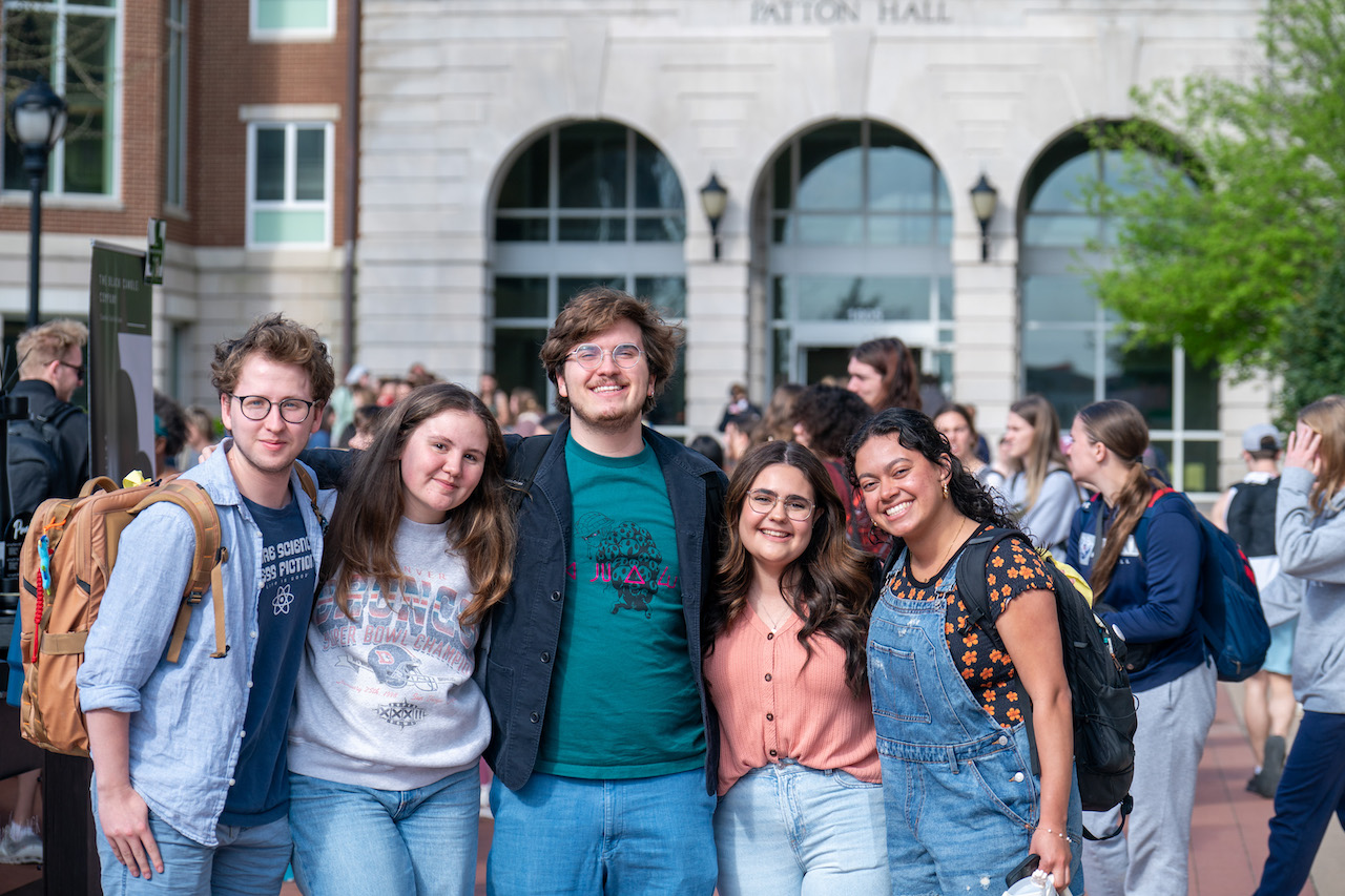 Five students smiling for a group picture on campus