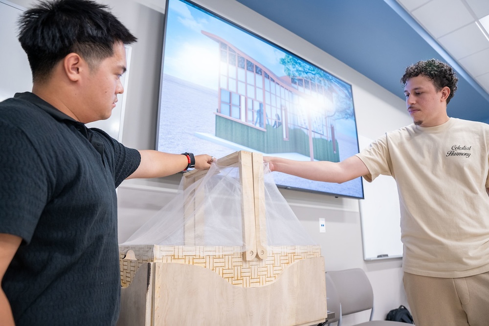 Two students hold up their baby care box