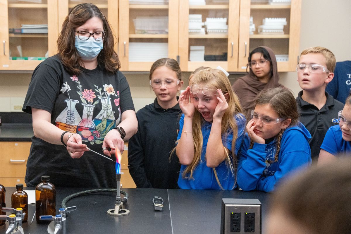 Dr. Danielle Garret and elementary students at an outreach event. The students stare amazed, mouths wide open