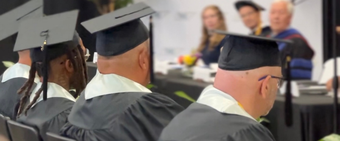 Graduates in caps and gowns sit at the inaugural Turney Center commencement ceremony.