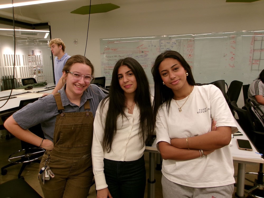 three students smile in classroom