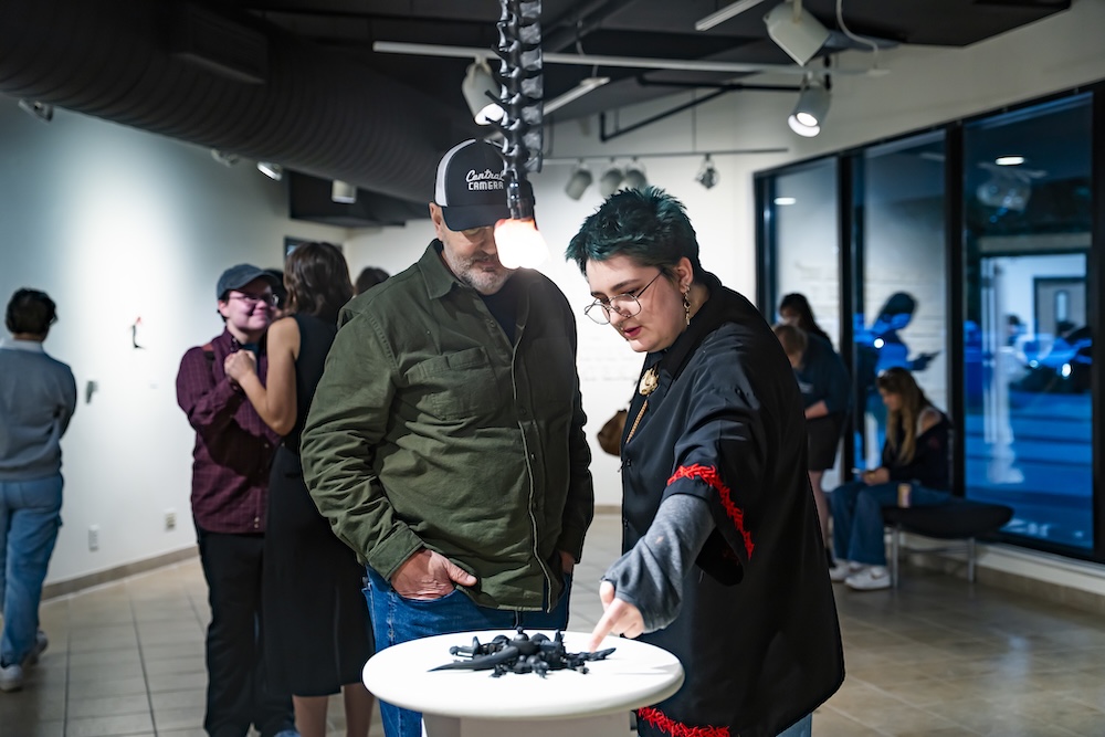 two people pointing at one of the pieces in the gallery