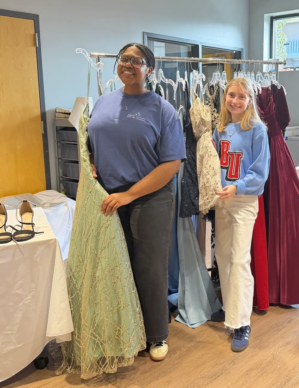 Students standing in front of formal wear clothing rack