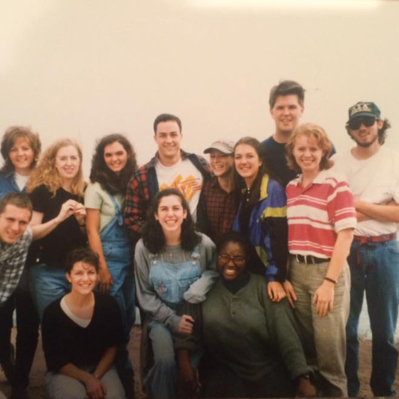 Smiling diverse group of young adults, dressed casually, posing for a group photo.