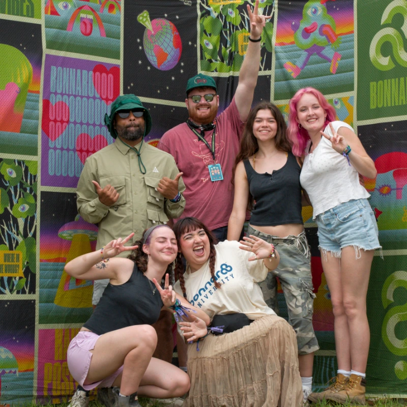 A group of smiling students and faculty outside on a sunny day