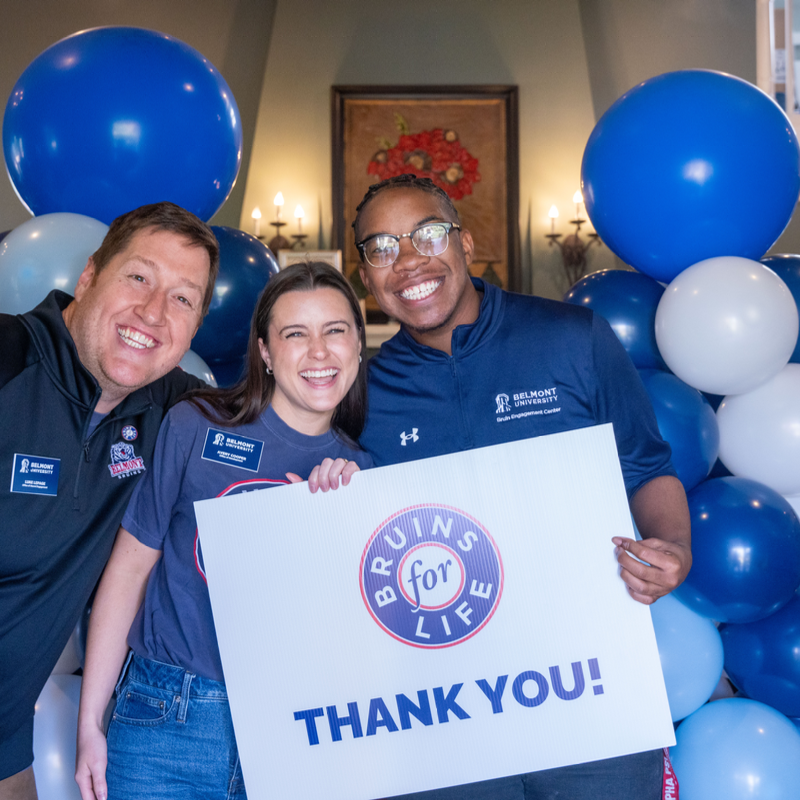 Belmont University staff and students smile, holding a 'Bruins for Life, Thank You!' sign at a campus event.