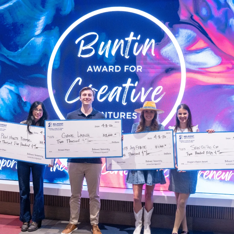 Four students holding big checks