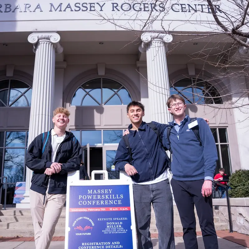 Students smiling by Powerskills Conference sign