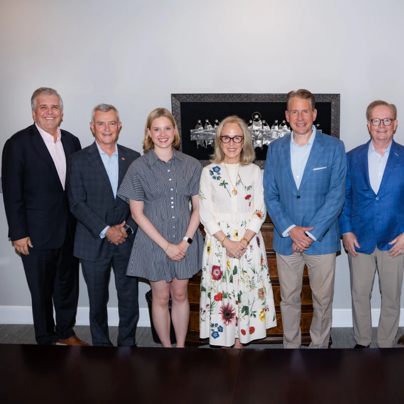 Group photo of eight business professionals, including executives and board members, in a corporate setting.