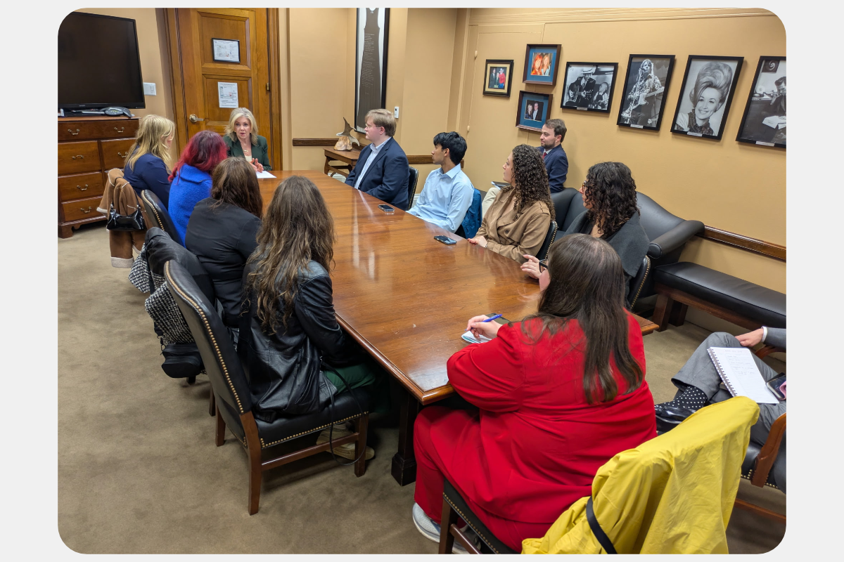 Group of people seated around a conference table in an office, participating in a professional discussion.
