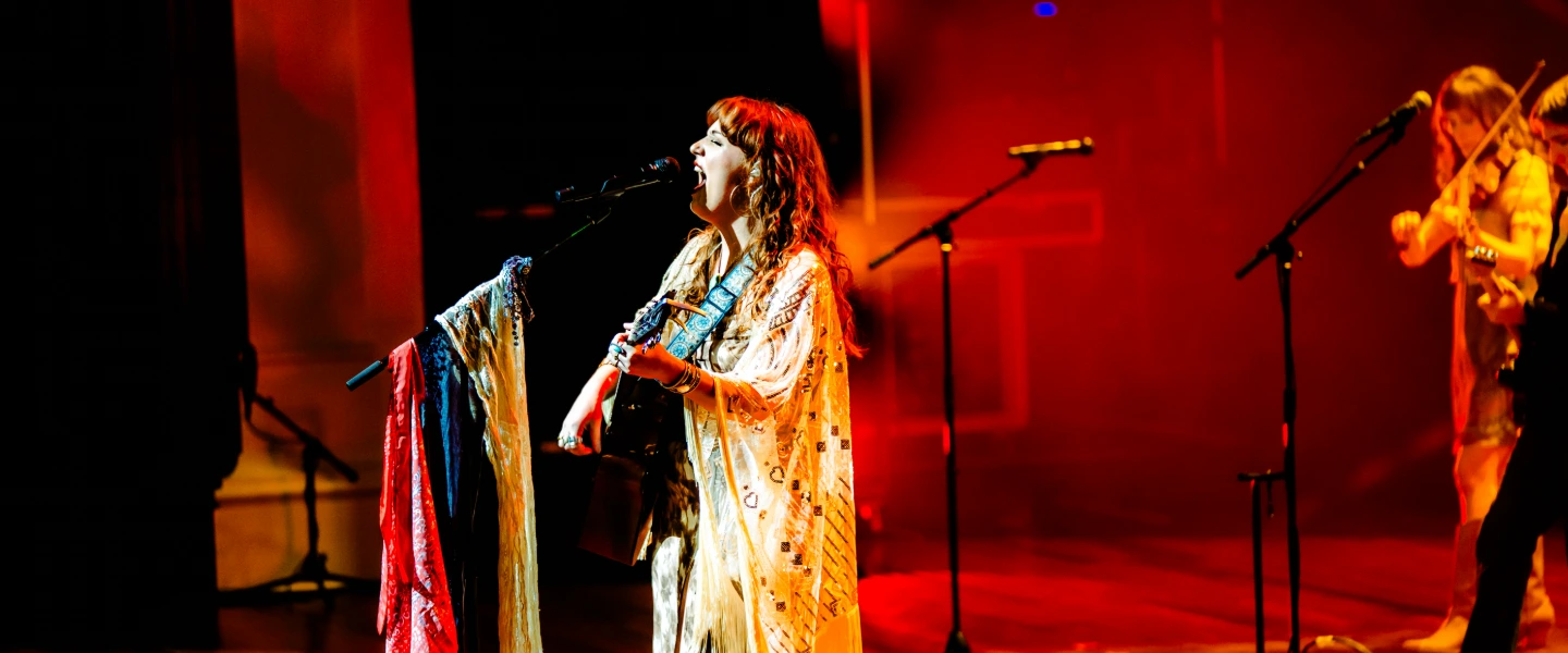 A performer singing onstage with a guitar