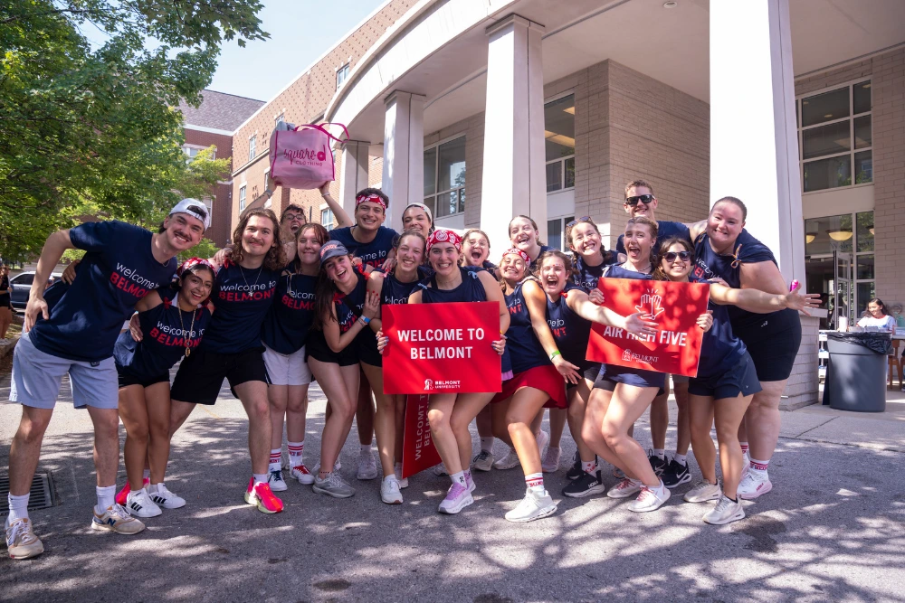 Belmont University students welcome new arrivals with "Welcome to Belmont" signs during campus orientation.