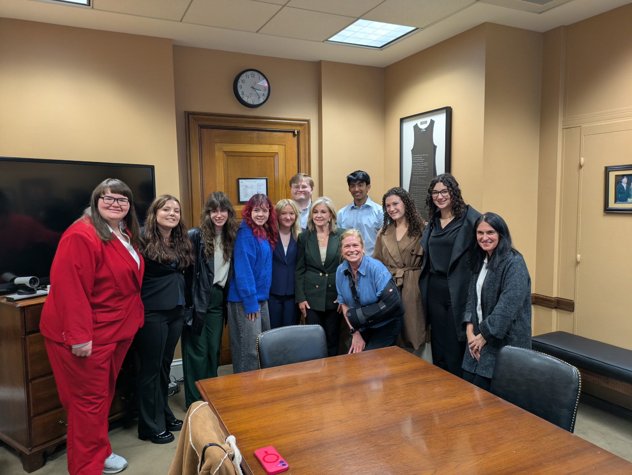 Diverse group of students and professionals smiling in a conference room.
