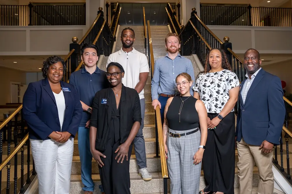 Group photo of Belmont University Faculty Fellows standing on a staircase inside a campus building.