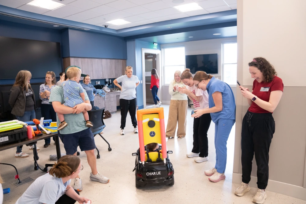 Students cheering on a child in a custom car