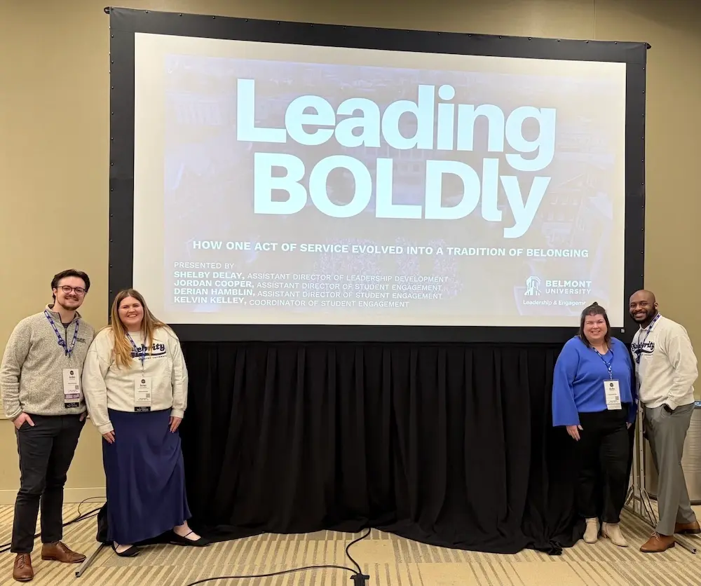 Four members of the Leadership & Engagement team in front of presentation display