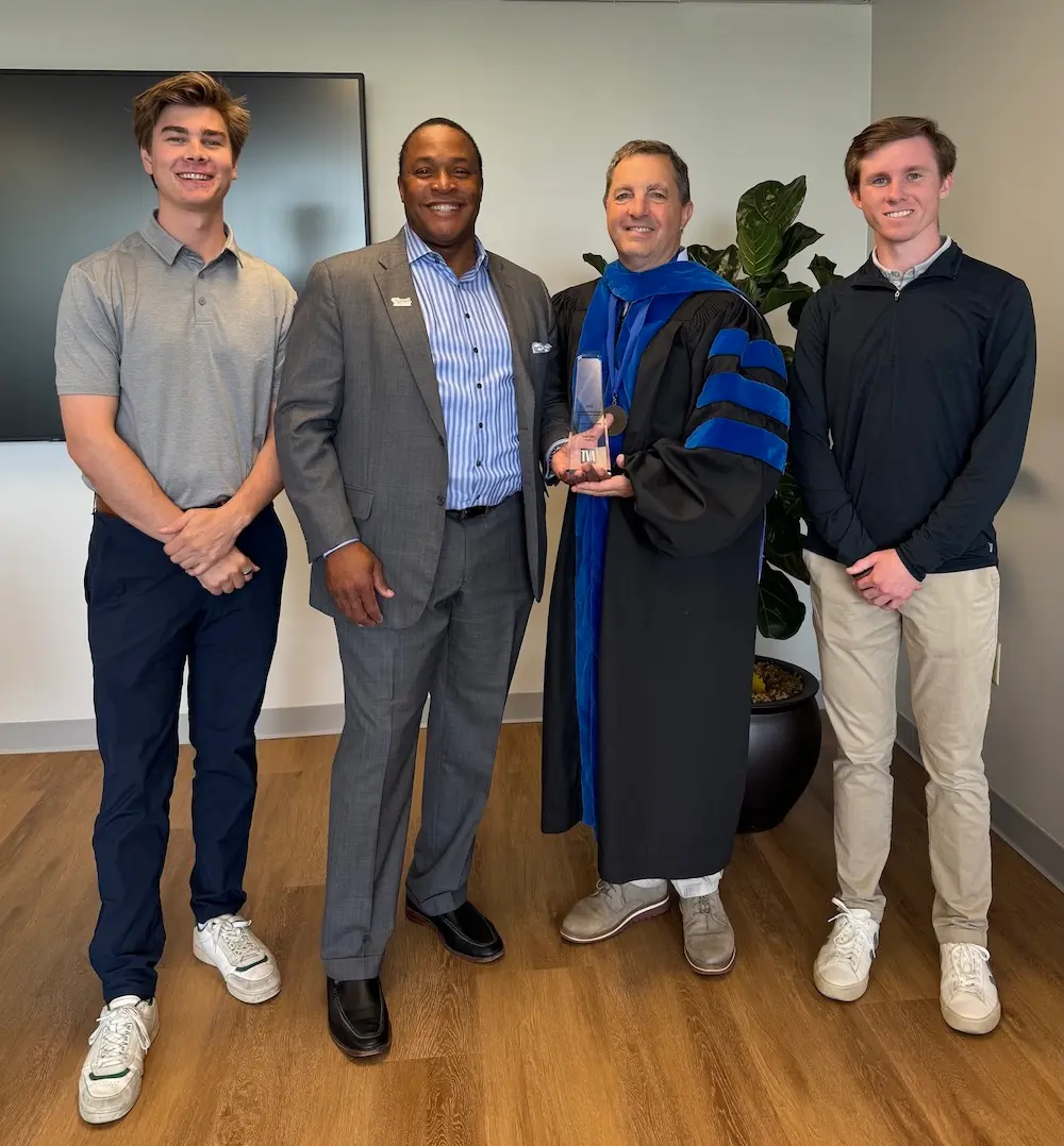 Students presenting award to professor and dean