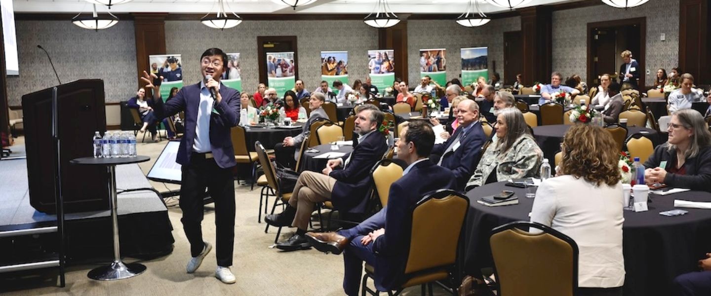 LearningWell Conference attendees; presenter speaking, gesturing with hand in front of crowd