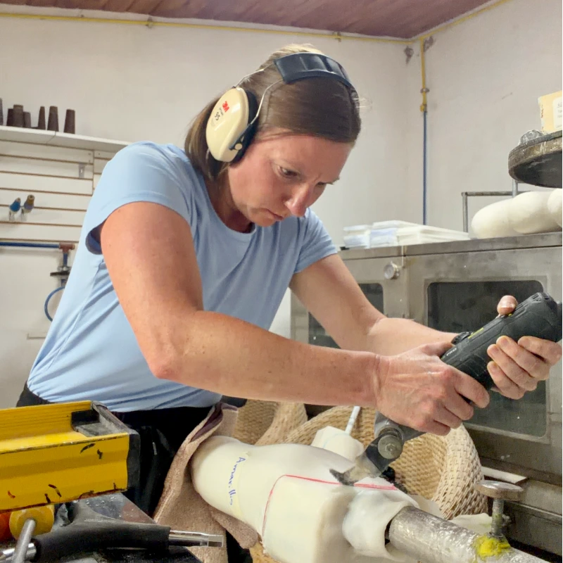 MSOT student Kim Cassidy in a prosthetics development shop carving a prosthetic with a power saw
