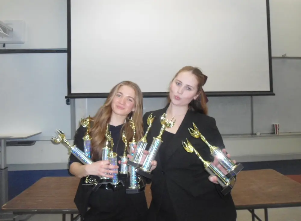 Ava Munyer and teammate with speech and debate trophies